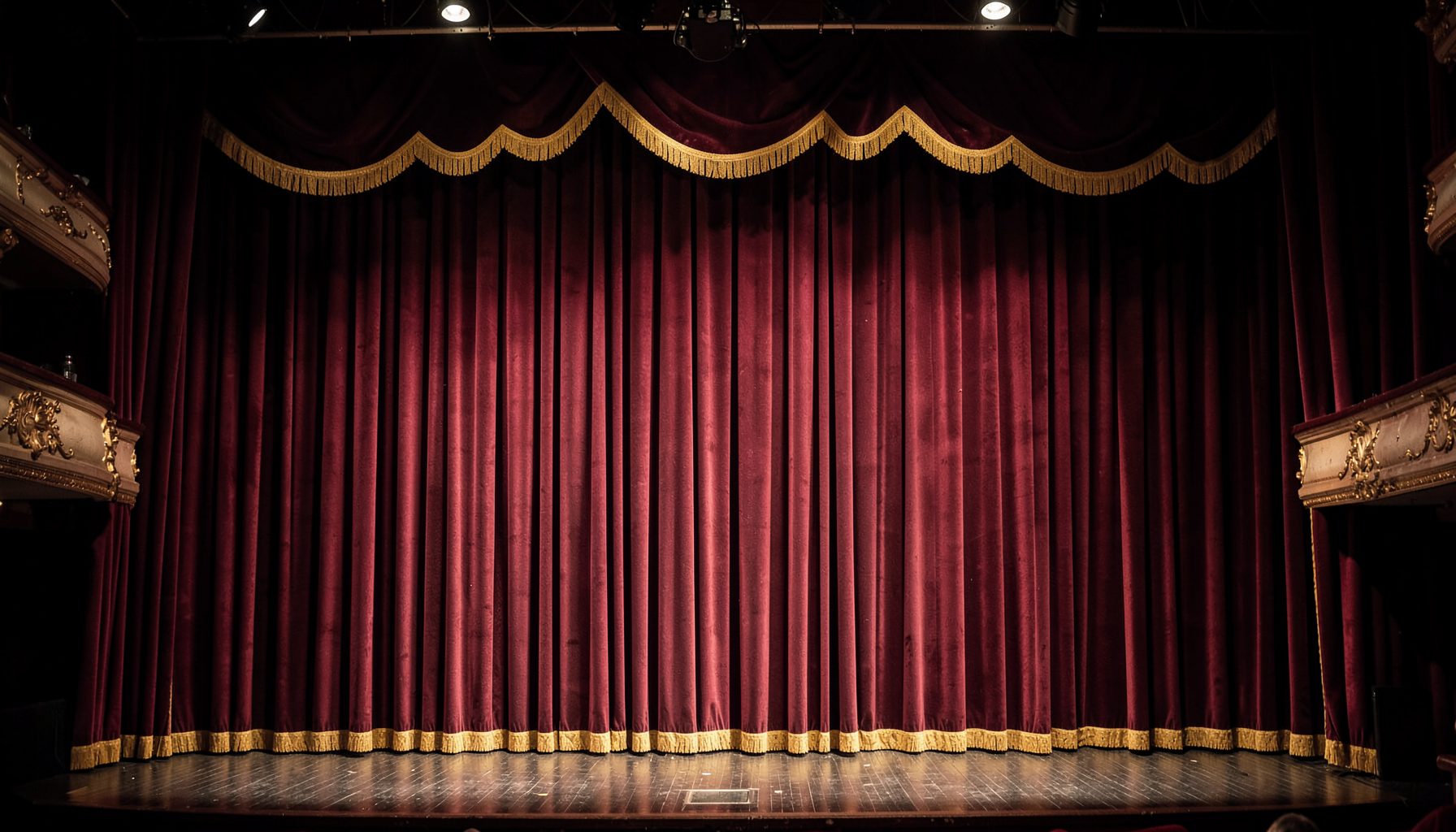 A vintage theater stage with heavy velvet curtains in deep burgundy and gold, softly lit by footlights, evoking the glamour of early 20th-century vaudeville.
